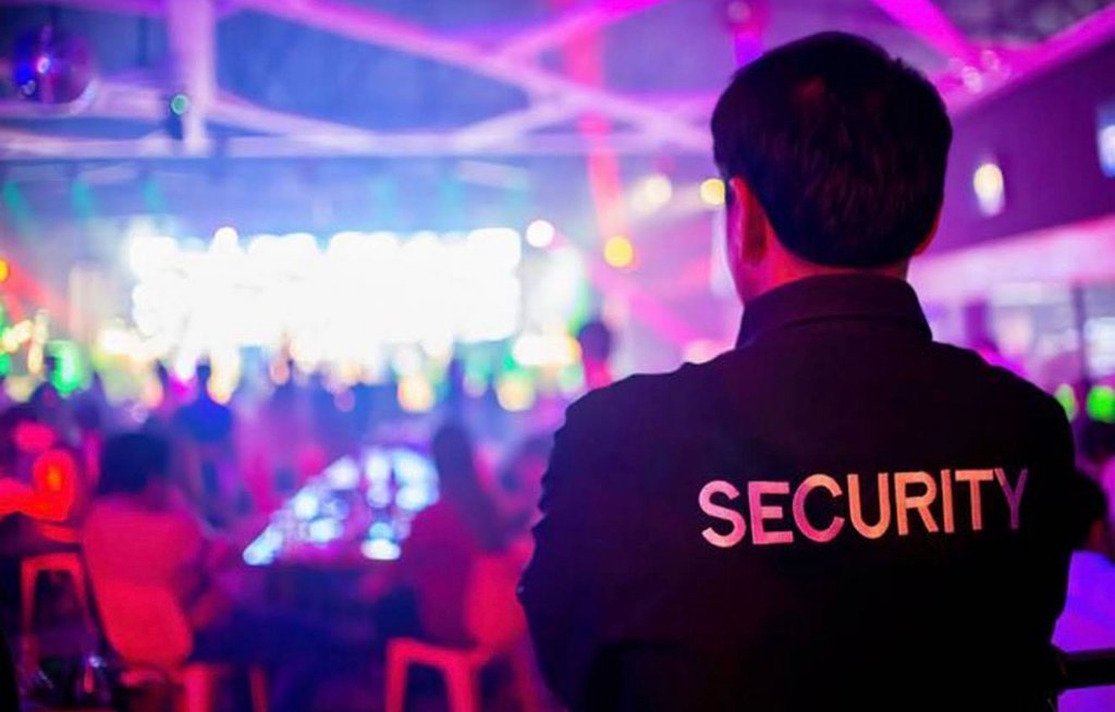 Security officer watching a crowded event from the back of the room