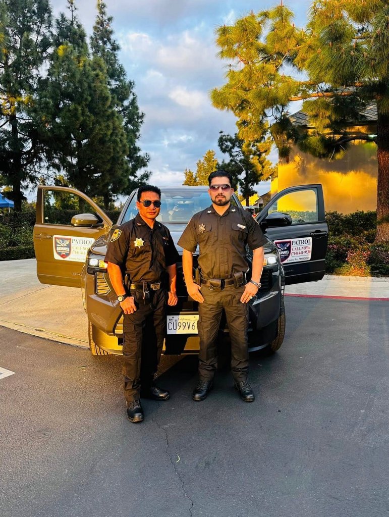 Two Guard For America officers standing with a marked patrol truck